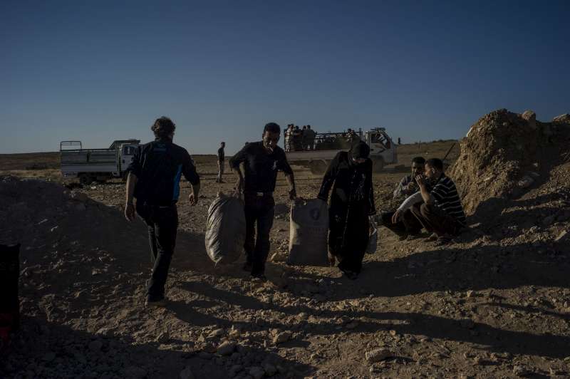 Syrians fleeing the war carry their belongings across the border from Syria to Jordan.