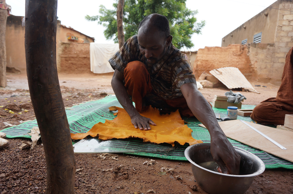 Bebe gets ready to work on leather products in the courtyard where he lives together with six other refugees and a Nigerian family.  UNHCR / Paul Absalon