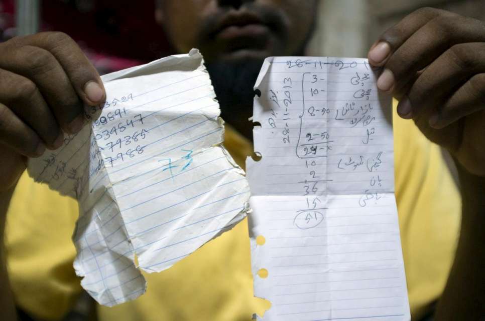 Abdul Rashid holds up notes he took during his journey on smugglers' boats from Maungdaw, Myanmar, to Kuantan, Malaysia, in late 2014.