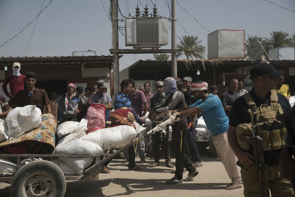 A man uses a pushcart to move goods near the Bzeibiz Bridge in Iraq.