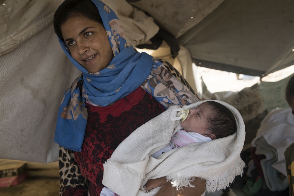 Abeer holds her newborn child in a makeshift camp near Bzeibiz Bridge in Iraq.
