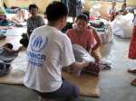 A UNHCR staff member hands out blankets to people displaced by Cyclone Nargis at a temporary shelter in Yangon, Myanmar.