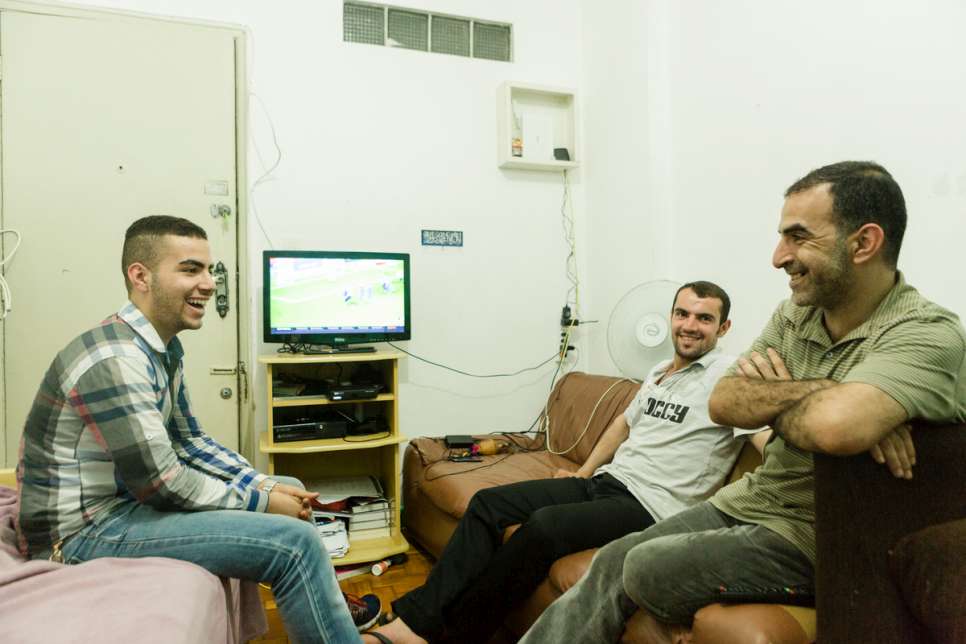 Moustafa (left) watches television with his uncle Zaher and father Khaled after the evening meal at their apartment.