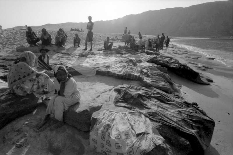 Rassemblés sur la plage d'Al-Bedha à l'aube, des réfugiés éthiopiens, arrivés la nuit précédente, font sécher leurs vêtements sur des rochers. Les passeurs les ont jetés par dessus bord, à quelques encablures de la côte, après que des soldats yéménites aient tiré sur leur bateau.