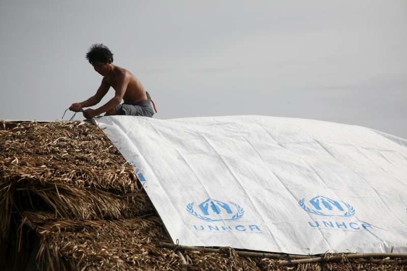 Le toit d’une maison, endommagé par le cyclone Nargis, est imperméabilisé grâce à une bâche en plastique du HCR à Yangon, au Myanmar. 