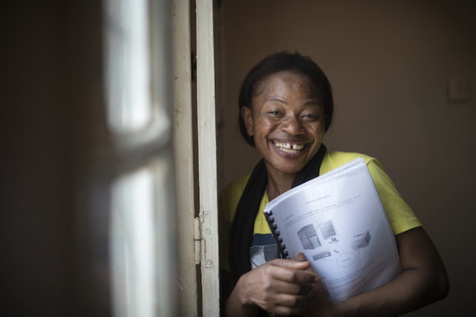 Budiaki holds her IT manual after finishing the day's classes, teaching computer basics to other refugees.