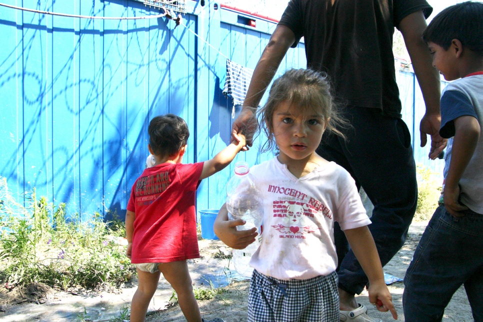 Une fillette se tourne vers l'appareil photo alors qu'elle collecte de l'eau au camp de fortune de Röszke. 