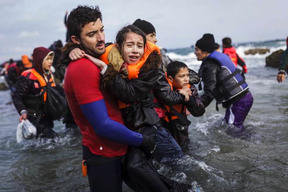 Un sauveteur bénévole aide une jeune Afghane à sortir de l'eau sur l'île grecque de Lesbos.