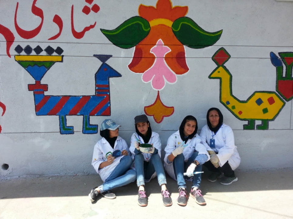 Un groupe de volontaires locaux prend une pause près de leur peinture murale. 