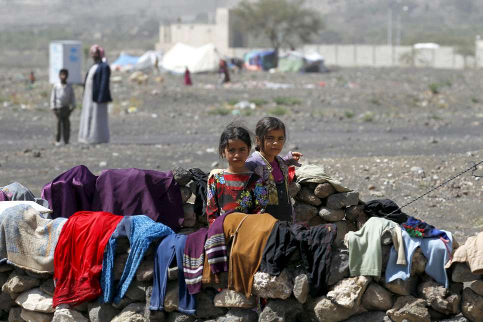 Two displaced Yemeni children – Muna, 9, and Swkina, 8 – stand outside their family's tent in Darwin camp, in Yemen's northern province of Amran.