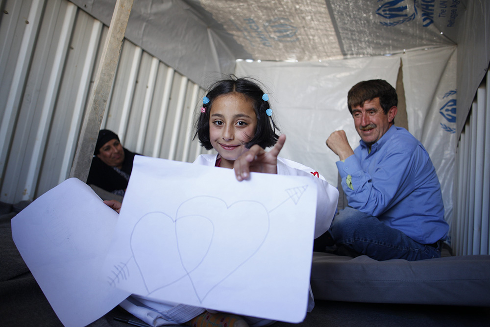 Jordan. Nine-year-old Syrian refugee, Solaf, draws with coloured pens at the caravan where she lives with her brother and parents at Azraq refugee camp