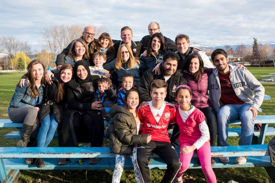 Mohammad, Sahar and their children gather for a photo with their sponsors and volunteers during an outing to the park.