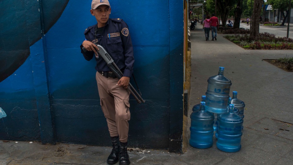 An armed security guard watches over a delivery of water bottles on a street in Guatemala City, where large areas are claimed by extremely violent street gangs. Their crimes range from kidnap and robbery to extortion and murder. The gangs' reach is international.