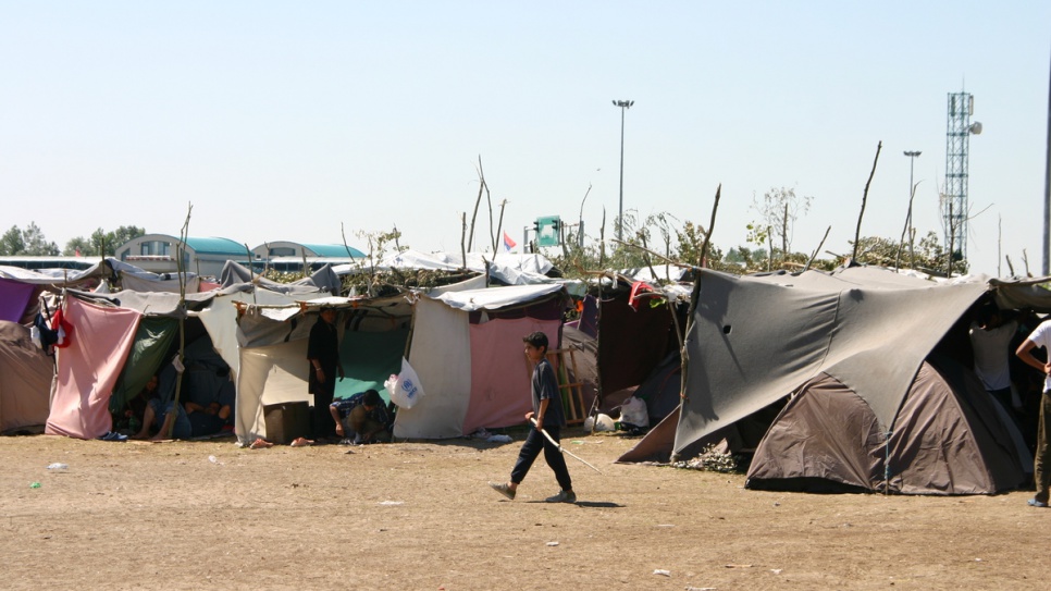 A boy walks past some of the hastily erected tents that house refugees as they wait to cross into Hungary.