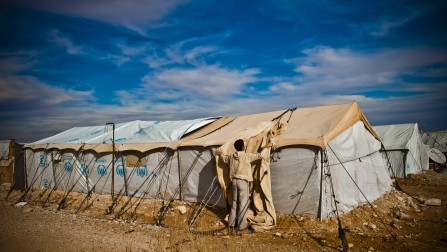 The camp's residents have so little to prevent themselves from the desert cold. A refugee is here trying to cover his tent as much as he can.
