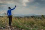 A young South Sudanese refugee tries to get a signal on his mobile pho...