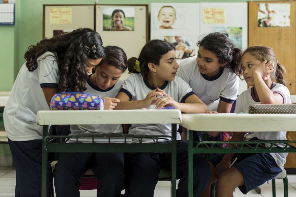 Syrian refugee Hanan Dacka (3rd from left), 12 years-old, confers with newly-made Brazilian friends (left to right) Anne Pinheiros de Souza, 12, Andressa Rabasco, 12, Julia Vanderlei, 12, and Maria Luiza de Sousa, 12, during classes at the Duque de Caxias Municipal School, in the Glicerio neighborhood of downtown Sao Paulo, Brazil, on February 25, 2016. Hanan arrived in Sao Paulo with her mother, Yusra Bakri, in early 2015 and was recognized as a refugee by the Brazilian government on September of that year. After only 4 days in a new classroom, she has started to make new friends, all of which already used to study alongside immigrants and refugees. Glicério, the school's neighborhood in the center of Sao Paulo, is the region to where the majority of immigrants and asylum seekers go to live as soon as they arrive in the city. Many children of those newly-arrived go to Duque de Caxias for elementary studies.