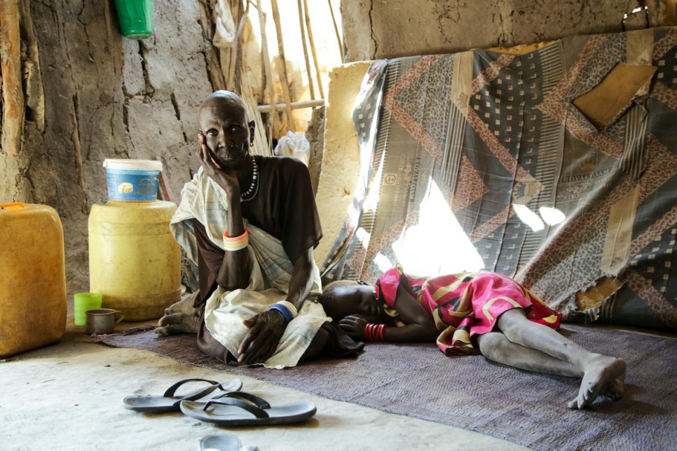 Nyapar Galuak, 60, rests next to her granddaughter inside their mud hut. They fled from Mayendit in mid-November 2015 due to fighting and hunger.