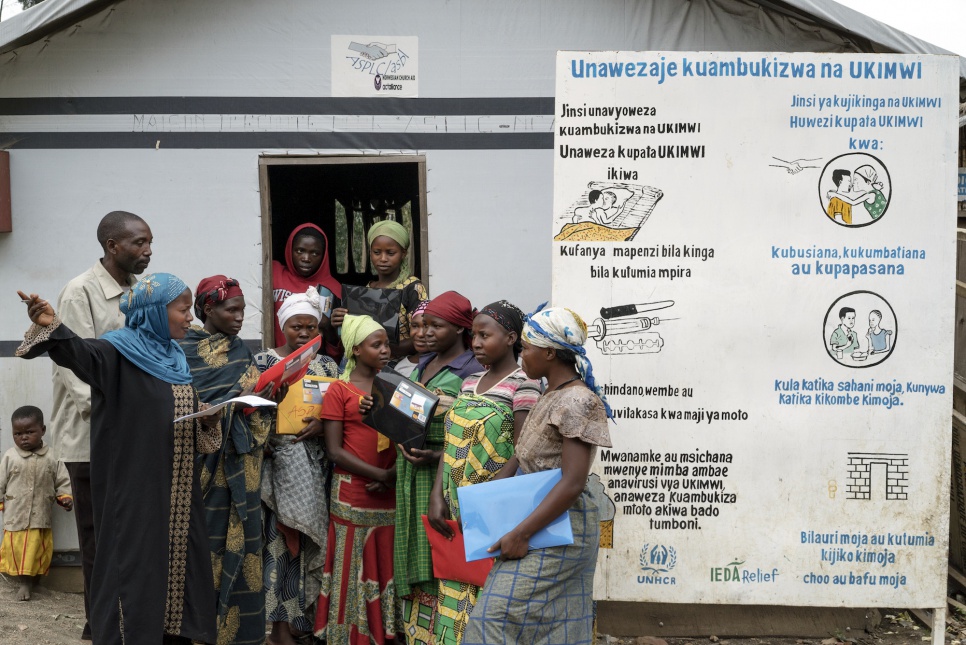 Women in Kalinga IDP camp speak with one another next to a sign warning about the dangers of HIV/AIDS.