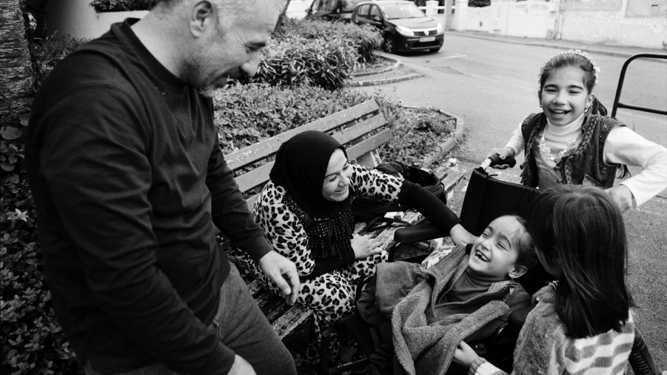 Aya laughs with her family in the garden outside their new flat in Laval, France.