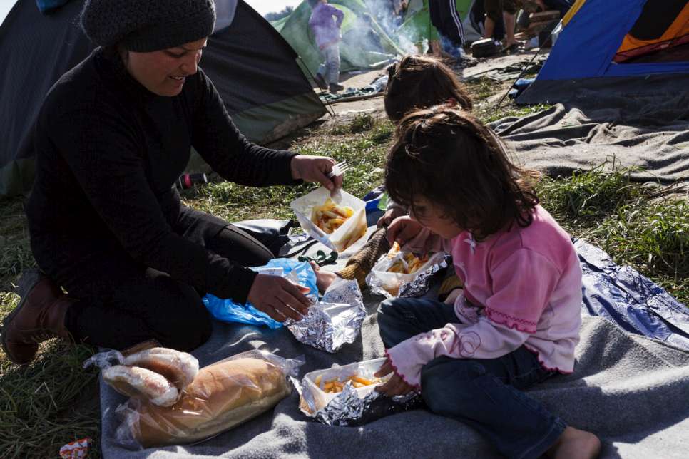 Nisrine feeds her two youngest children outside the small camping tent where the family sleep.