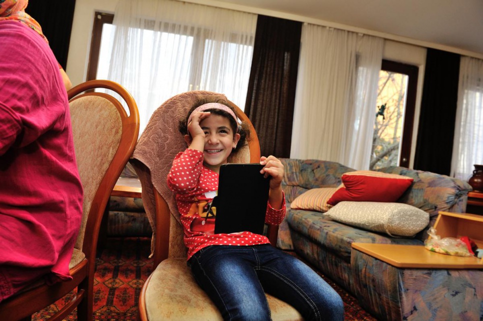 Six-year-old Thuraya laughs as she looks at a tablet computer.