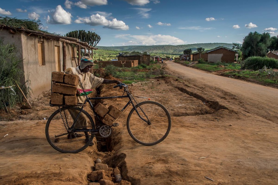 Burundian refugee Cedric Ishimimara, 15, delivers mud bricks to a customer in Kashojwa village.