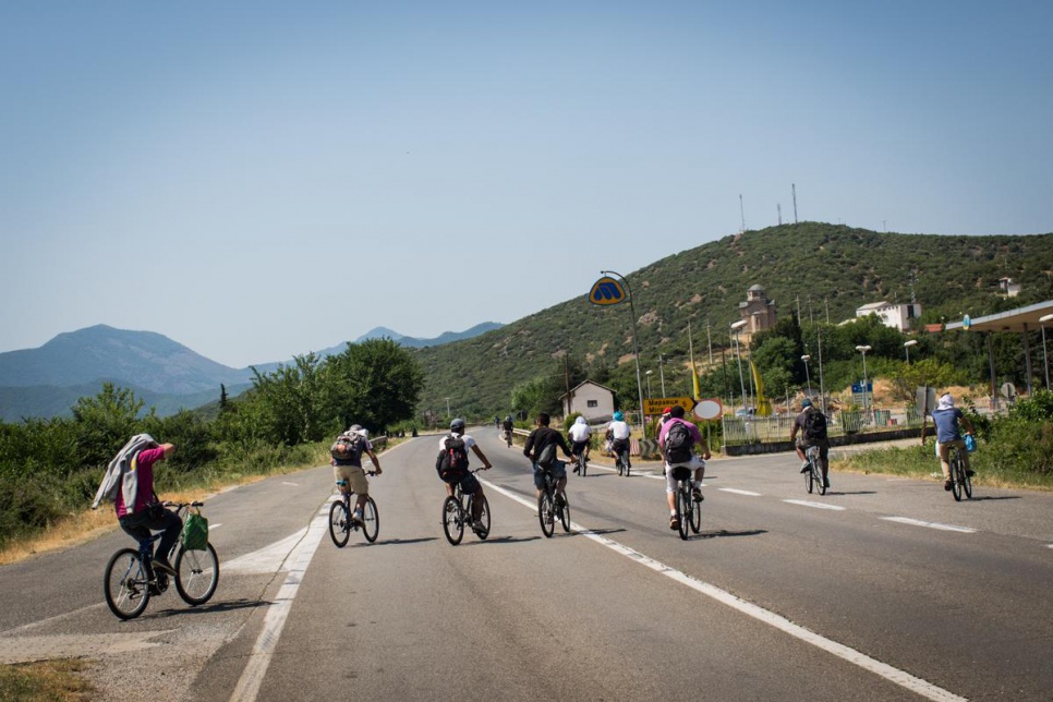 A group of Syrian refugees cycle along the road leading north from fYROM's border with Greece.