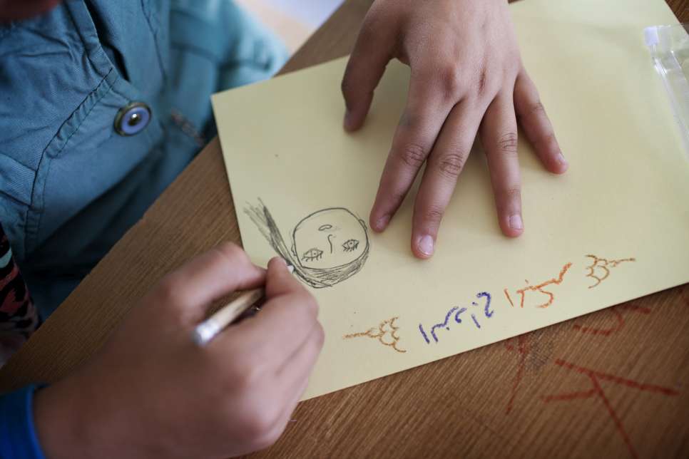 A teenage girl draws a face with the words 'early marriage' at one of Omaima's classes.