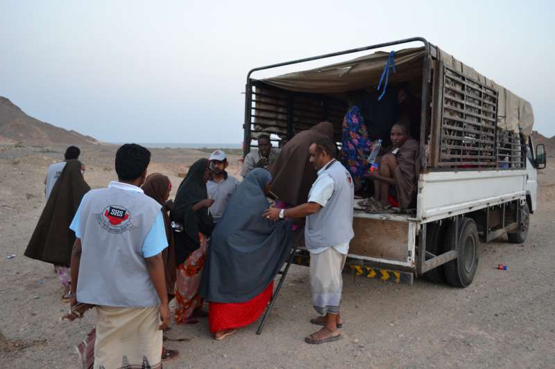People are helped into trucks for transport to Mayfa'a Hadjar Transit Centre, where they will receive food, a place to sleep and medical care.