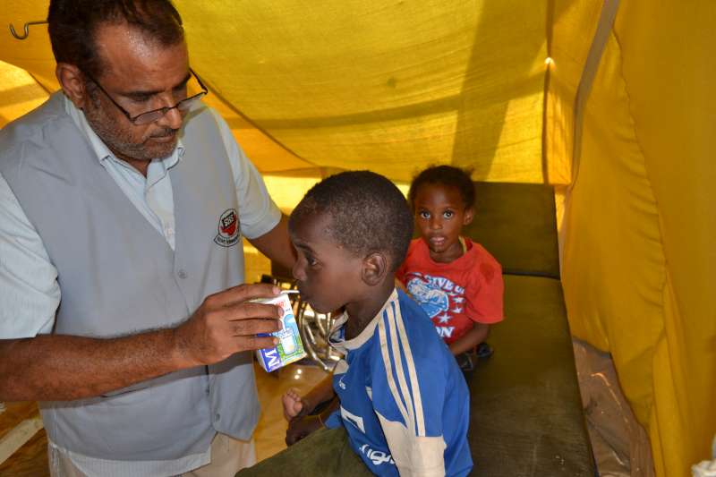 The director of SHS, Nasser Salim Ali Al-Hamairy, gives milk to newly arrived children in Mayfa'a Hadjar Transit Centre.