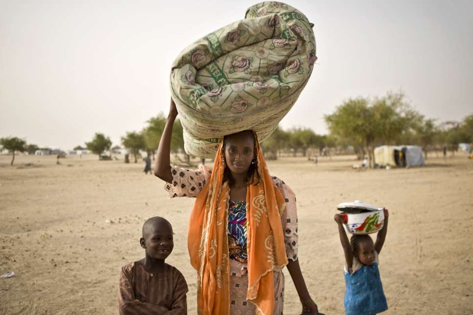 Zara, âgée de 26 ans, son fils Ousseini (8 ans) et sa fille Aïcha (4 ans) transportent des effets personnels au site où Bala, le mari de Zara, a entrepris la construction d'un nouvel abri, au camp de réfugiés de Sayam Forage. 