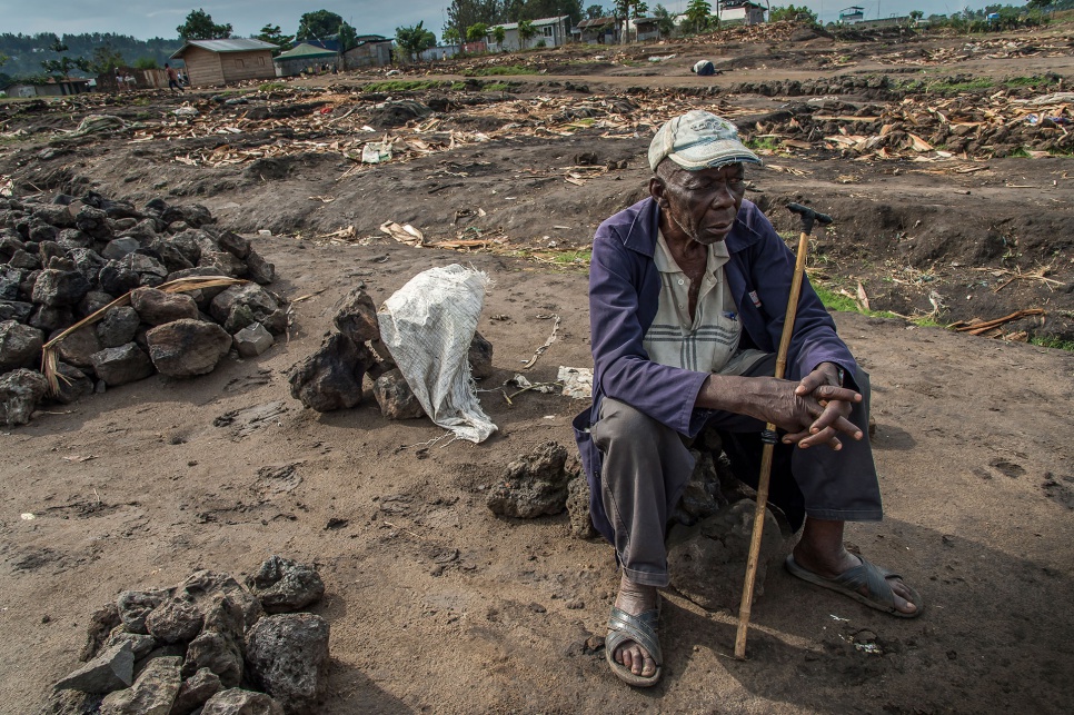Flory, 70, gazes at the settlement's charred ruins. He is afraid to return to his village in Bwito district, where he says armed groups would put his life in danger.