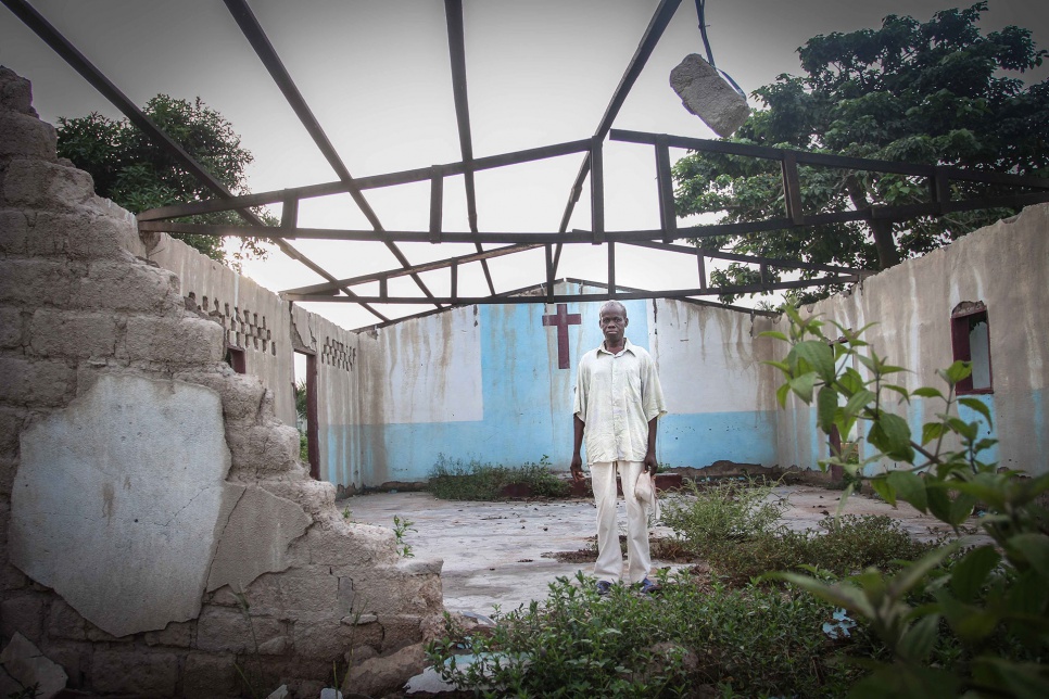 Deacon Ambroise stands inside the shell of his former church, which was looted and burnt by attackers. "I want to rebuild it, before my own house," he says.