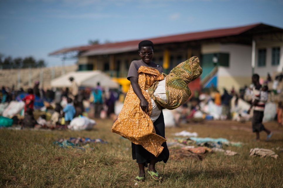 Silvane, Foibe's 20-year-old daughter, picks up her belongings after her arrival at Kigoma Stadium, which is serving as a reception centre for refugees.