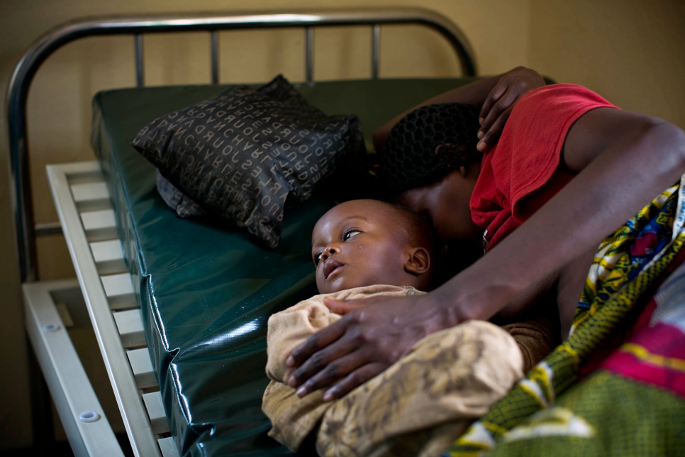 Zénobie, 29, who is thought to be suffering from cerebral malaria and pneumonia, tries to breastfeed her son at the emergency health post in Bugesera reception centre, Rwanda.