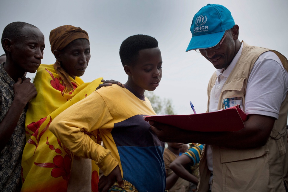 Paul, a UNHCR staff member, registers refugees from Burundi as they prepare to board a bus that will take them from Bugesera reception centre to Mahama refugee camp in Rwanda.