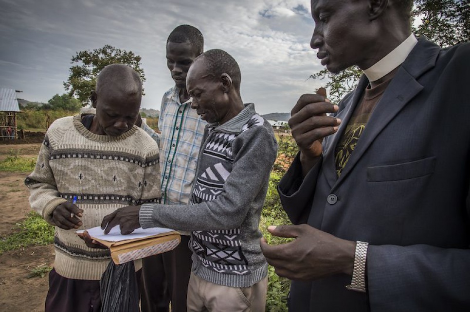 Peter Kenyi, a local landowner, signs a document with a local government official to hand over the rights to his land so that Alaak can expand the school.