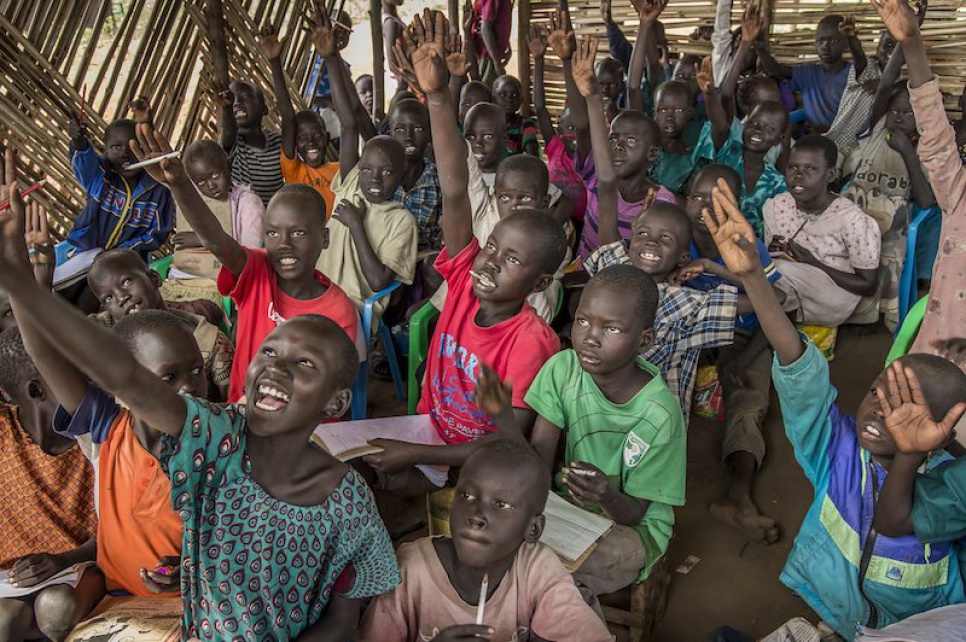 Refugee children from South Sudan eagerly raise their hands to answer Alaak's question.