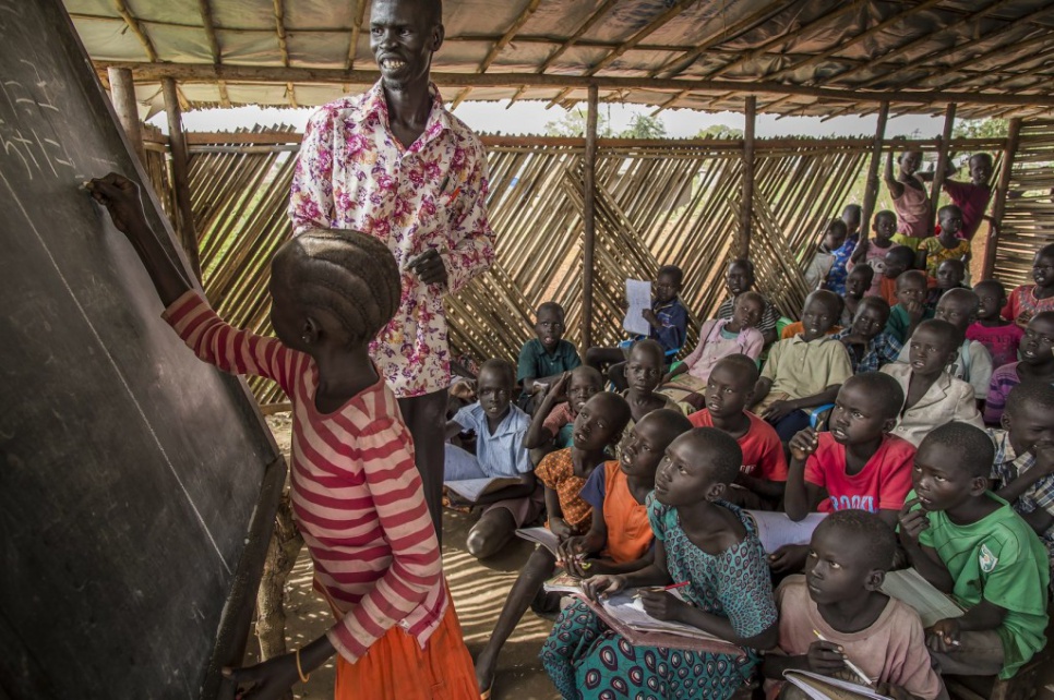 Alaak leads a math class for young refugees at Nyumanzi settlement in Adjumani, Uganda. He and a volunteer, his cousin John, teach 500 students each day.