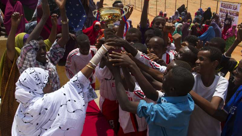 Mama Hawa hands a trophy to the winning team in a football tournament. The GECPD offers vocational training for boys, and provides food and non-food relief to the displaced. 