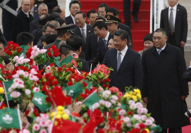 China's president Xi Jinping and his wife Peng Liyuan are greeted by officials upon arrival at Macau International Airport, Dec. 19, 2014.