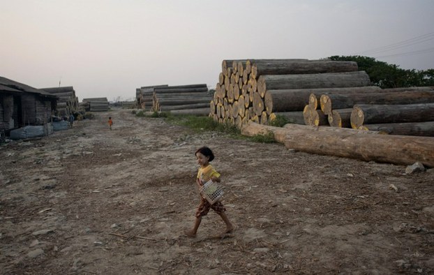 A girl carries a basket at a logging area on the outskirts of Yangon, May 4, 2014