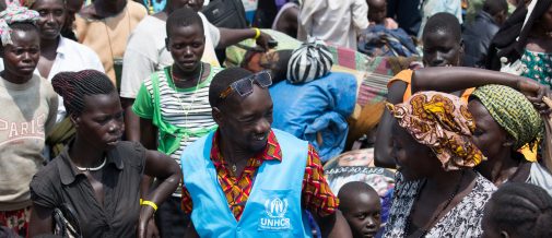 A UNHCR aid worker guides a South Sudanese refugee through the crowd as she moves her belongings from the border to temporary accommodation in Elegu, Uganda. ; More than 43,000 South Sudanese refugees crossed into Uganda between 7 July and 27 July 2016 following an outbreak of fighting in Juba between forces loyal to President Kiir and First Vice President Machar. At least 300 people were killed in the violence that erupted in the capital. 

The refugees came into Uganda via border crossing points at Moyo, Kuluba, Lamwo, Yumbe and Elegu and the numbers increased when government authorities opened the border into Uganda at Nimule and cleared the 200-kilometre Juba-Nimule road of checkpoints. 

Many refugees travelled on convoys of trucks, taking their belongings with them. Ninety per cent of the refugees are women and children. Many have arrived at the newly established Pagarinya 2 settlement in Adjumani District, northern Uganda, while others are waiting at collection points to be transferred to the settlement. 

UNHCR estimates that nearly one in four South Sudanese citizens are displaced within its borders or in neighbouring countries due to conflict and food shortages, and the total number of South Sudanese refugees could exceed 1 million this year.