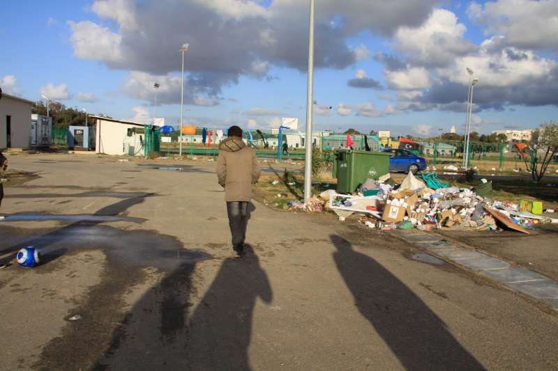 أحد القاصرين غير المرافقين يبلغ 12 عامًا يمر بجانب القمامة في موقع السكك الحديدية. وقد تُرك وحيدًا بعد أن مات عمه بسبب الملاريا أثناء رحلته من الصومال إلى ليبيا بحثاً عن الأمن وحياة أفضل.