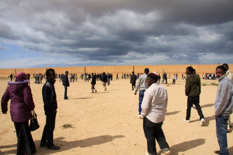 أشخاص من إفريقيا جنوب الصحراء الكبرى، من بينهم صوماليون وإريتريون، يتجولون في الساحة الواسعة لمركز الاحتجاز في بنغازي.
