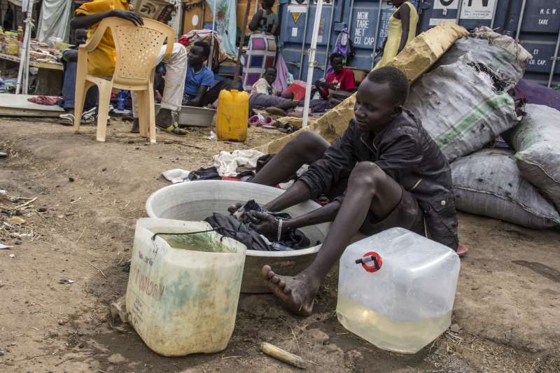 مراهق تعرض للنزوح جراء العنف الأخير، يقوم بغسل الملابس في وعاء داخل المجمَّع التابع لبعثة الأمم المتحدة في جنوب السودان، الذي أصبح مخيماً مؤقتاً لقبيلة النوير.  