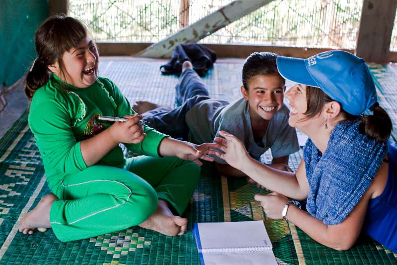 Aya and Labiba share a light moment with UNHCR staff member Roberta Russo in their family home. 