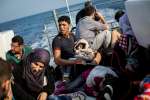 Syrian refugees rest onboard a Hellenic Coast Guard vessel after being...