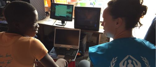 UNHCR Emergency Lab Manager sits with a young refugee boy in Malawi.